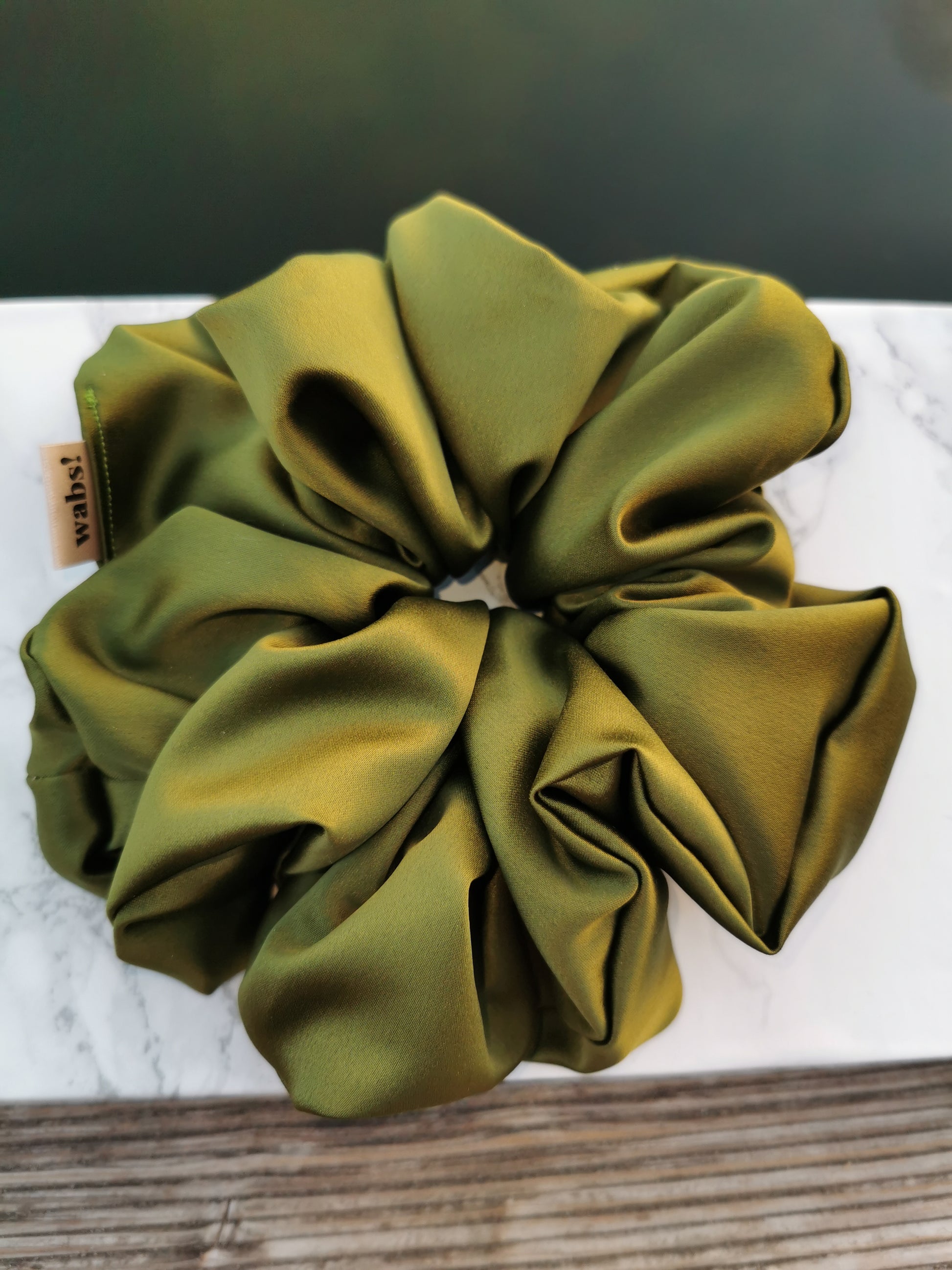 Olivegrüner Satin-Scrunchie, verleiht natürlichen Charme und hält das Haar sanft